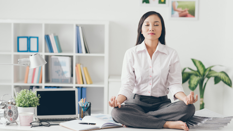 Mulher sentada em posição de meditação com os olhos fechados, buscando autoconhecimento para mudar de carreira.